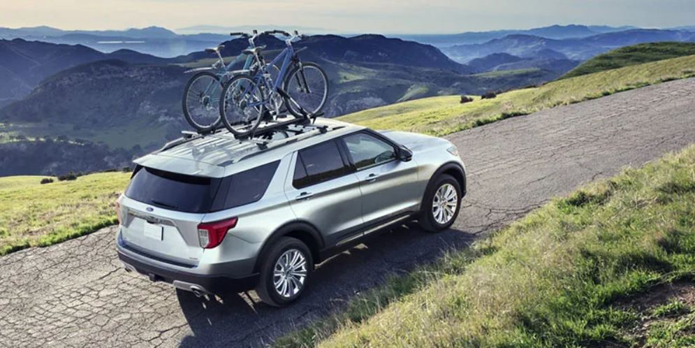 A silver 2022 Ford Explorer being driven on a paved road with mountains in the background. | Ford dealer in Jacksonville, AR.