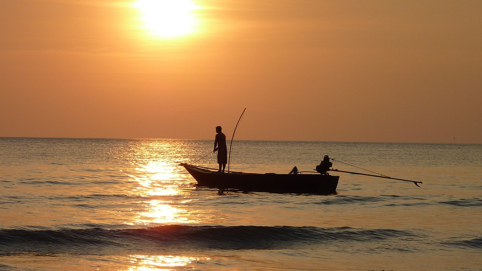 A man fishing on a boat with the sun setting in the background. | Fishing | Boating around Jacksonville, AR.