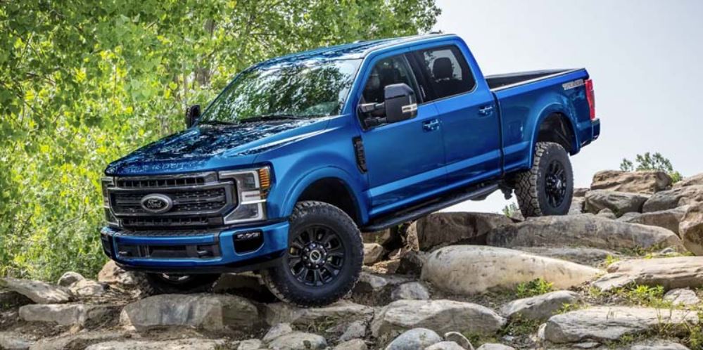 A blue 2022 Ford F-250 parked on large rocks with trees behind it. | Ford dealer in Jacksonville, AR.