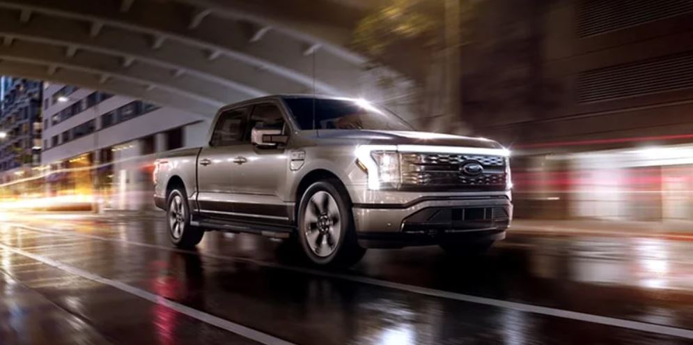 A silver 2022 Ford F-150 Lightning being driven on the wet highway. | Ford dealer in Jacksonville, AR.