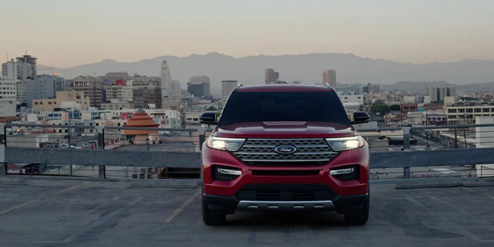 A red 2023 Ford Explorer parked with the lights on and buildings in the background. | Ford service in Jacksonville, AR.