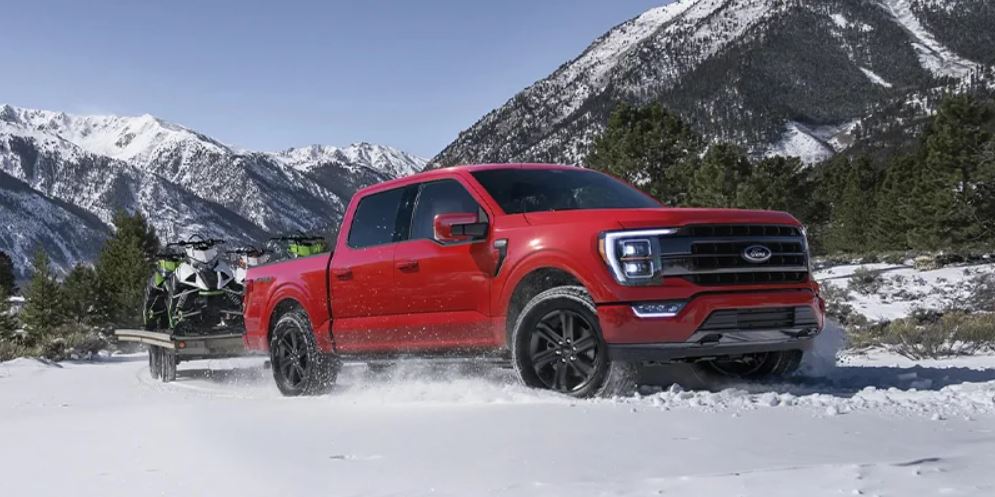 A red 2023 Ford F-150 parked in the snow with mountains in the background. | Ford dealer in Jacksonville, AR.