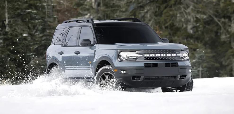 A gray 2023 Ford Bronco being driven in a wooded area covered in snow. | Ford dealer in Jacksonville, AR.